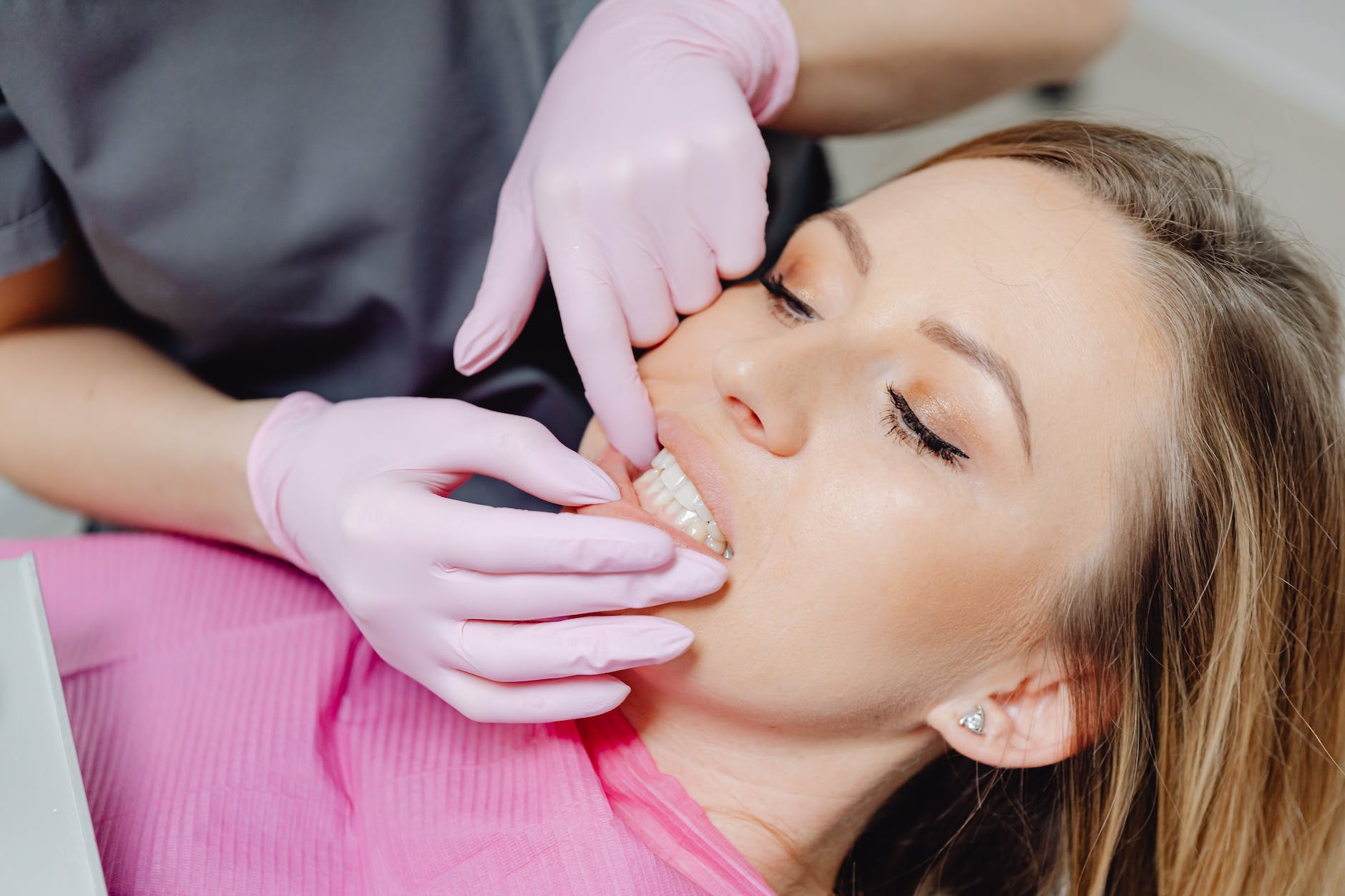 a person wearing latex gloves checking a woman s teeth